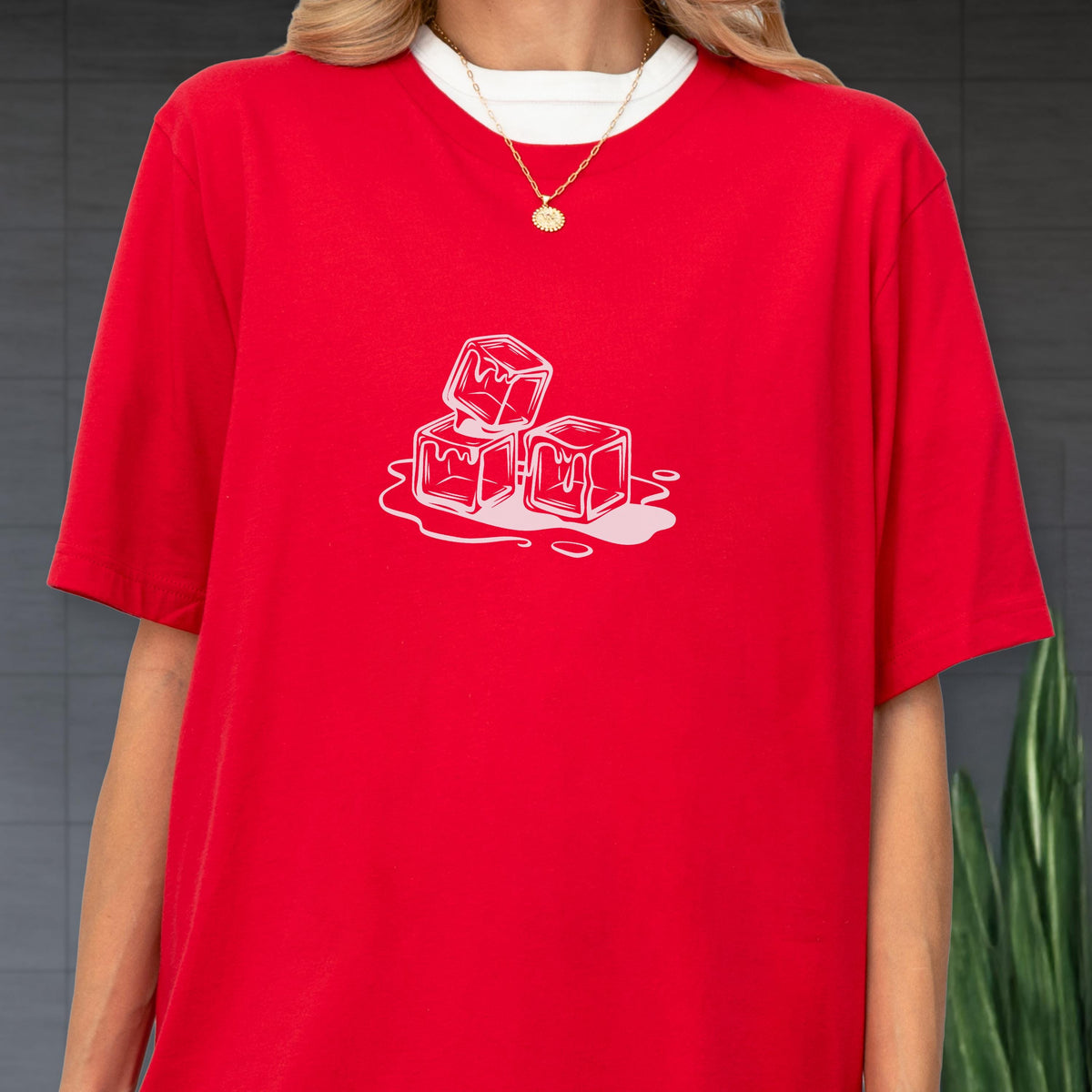 May include: Red t-shirt with a white crew neck collar and a white graphic of three melting ice cubes. The ice cubes are outlined in white, with white drips of water around them. The shirt has short sleeves.