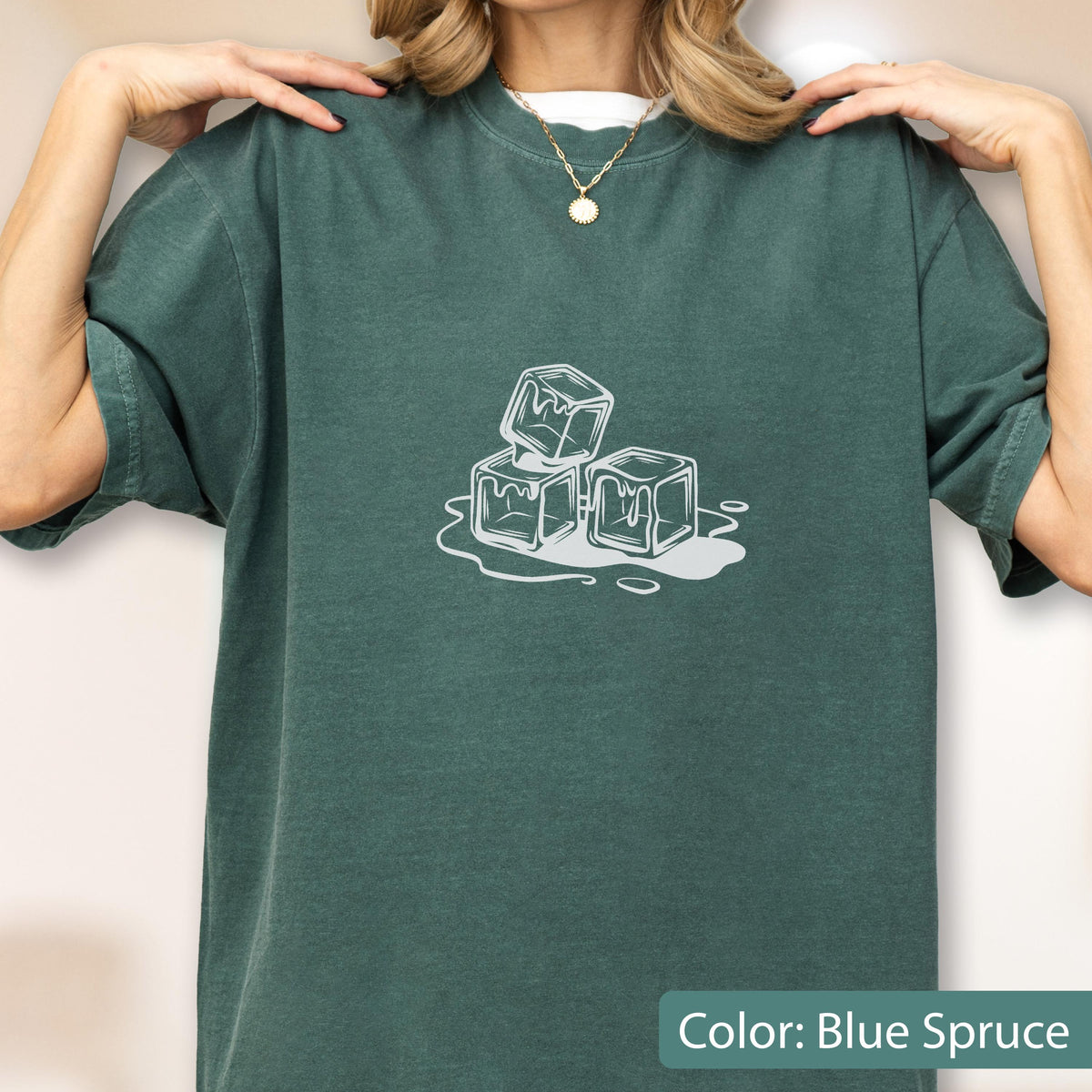 May include: Blue spruce-colored t-shirt with a white graphic of three ice cubes melting. The shirt has short sleeves and a crew neck. The text "Color: Blue Spruce" is at the bottom of the image.