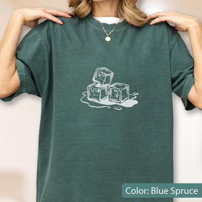 May include: Blue spruce-colored t-shirt with a white graphic of three ice cubes melting. The shirt has short sleeves and a crew neck. The text "Color: Blue Spruce" is at the bottom of the image.