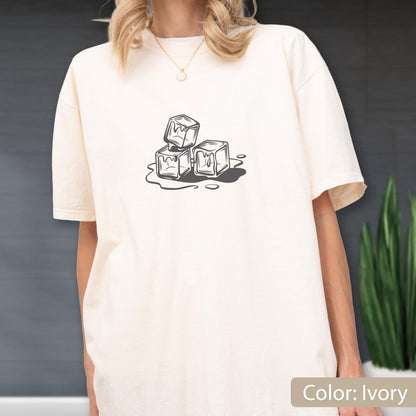 May include: Ivory-colored t-shirt featuring a graphic of three melting ice cubes. The design is in black and white, with the cubes stacked and surrounded by water. The shirt is a relaxed fit.