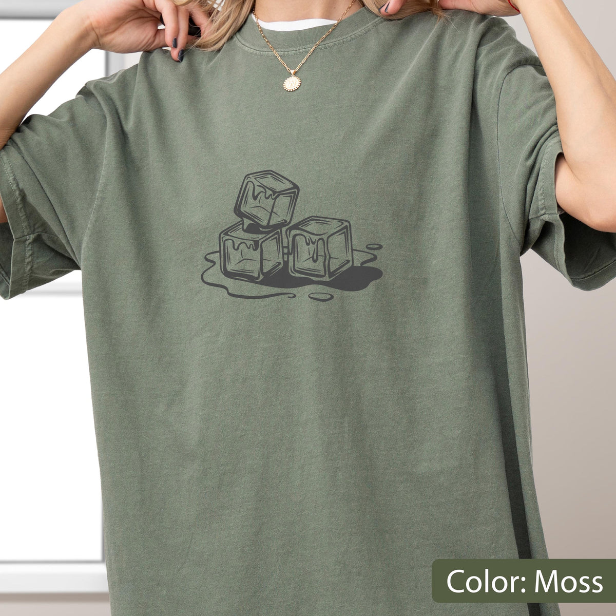 May include: A moss-colored t-shirt featuring a graphic of three melting ice cubes. The design is in shades of gray and black, with the text "Color: Moss" in the bottom right corner.