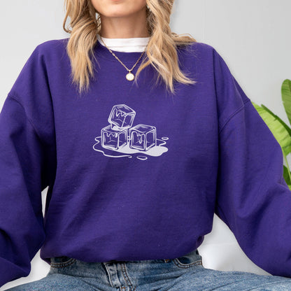 May include: A deep purple sweatshirt with a white graphic of three ice cubes melting. The sweatshirt has a crew neck and long sleeves. The graphic is centered on the chest.