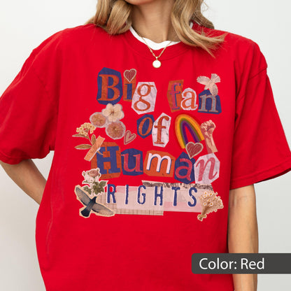 May include: A red t-shirt with the text "Big fan of Human Rights" in a collage style. The design includes a rainbow, flowers, and a raised fist. The shirt is a solid red color.