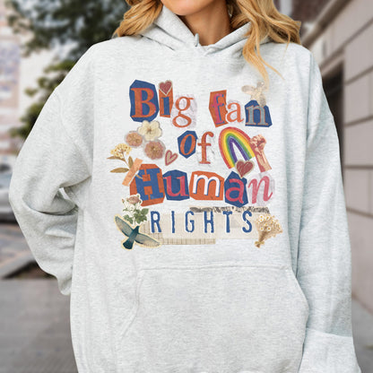 May include: A light gray hoodie with a graphic that reads "Big fan of Human Rights." The design incorporates a rainbow, hearts, and floral elements. The hoodie has a front pocket and a drawstring hood.