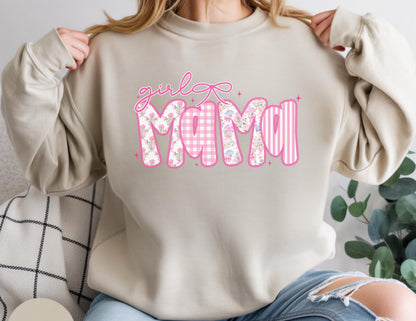 May include: A beige sweatshirt with the words "girl Mama" in pink. The word "girl" is in cursive, and the word "Mama" is in a mix of floral, gingham, and striped patterns. A pink bow is above the word "girl".