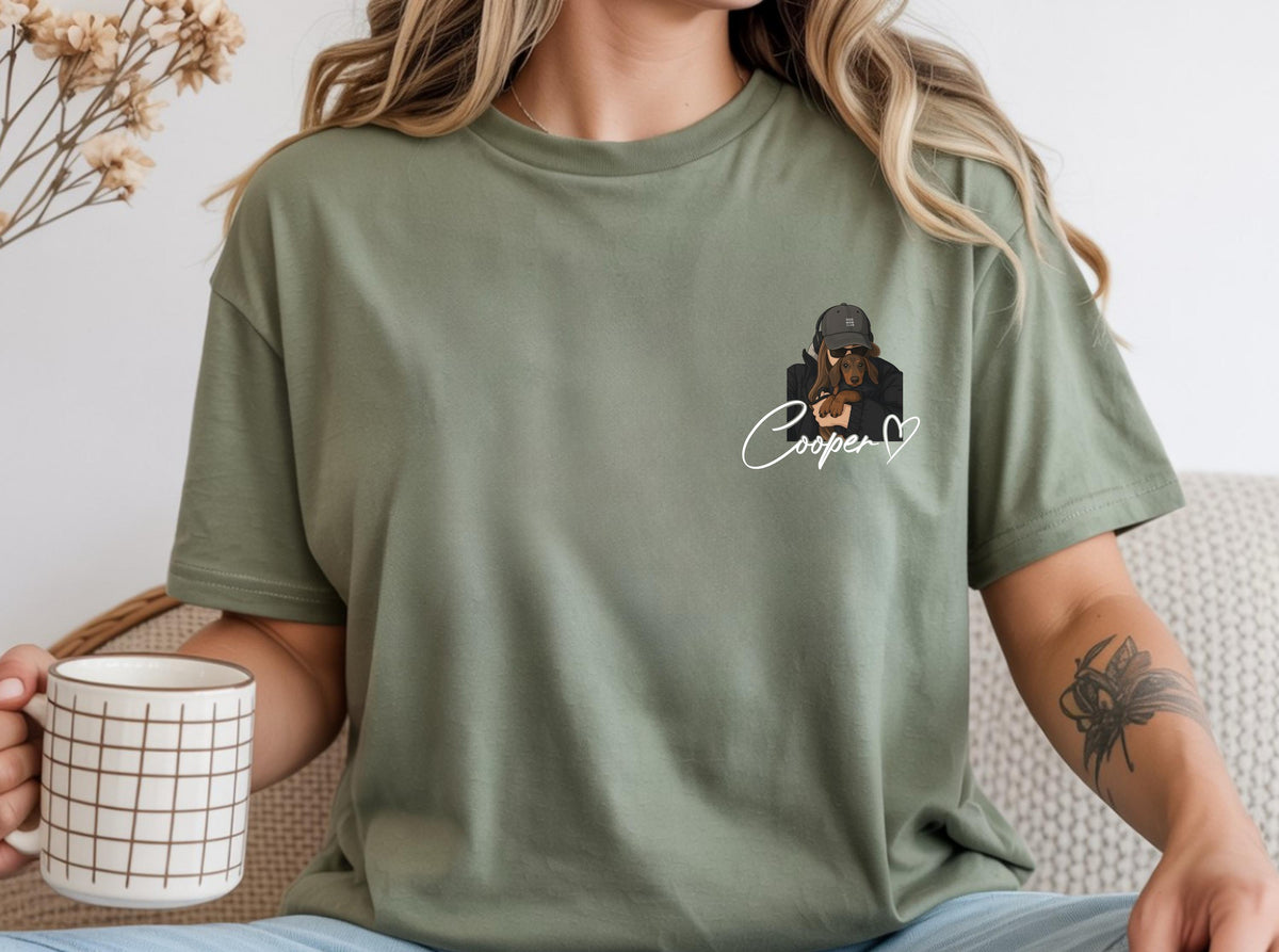 May include: Olive green t-shirt featuring a graphic of a dog wearing a cap and sunglasses, with the name "Cooper" in cursive and a heart. The shirt is a relaxed fit.