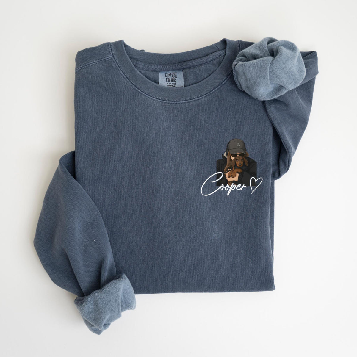 May include: A blue long-sleeve sweatshirt with a custom illustration of a dog wearing a hat and sunglasses. The dog is embraced by a person. The name "Cooper" is written in cursive with a heart.
