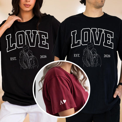 May include: Black t-shirts with the word "LOVE" in white block letters, a line drawing of a couple, and the year "2026". A maroon t-shirt has a white heart and the letter "A" on the sleeve. The shirts are likely for couples.