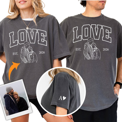 May include: Two charcoal gray t-shirts with the word "LOVE" in white block letters. Below the word "LOVE" is the text "EST. 2026" and a white line drawing of a couple. One shirt has the letter "A" and a heart on the sleeve.