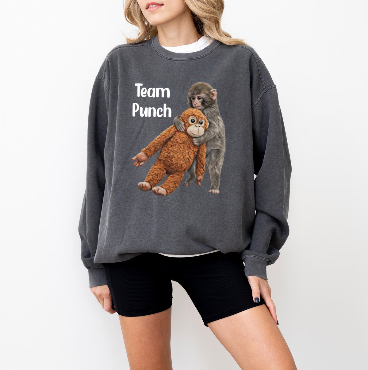 May include: Dark gray sweatshirt featuring a graphic of two monkeys, one hugging the other. The text "Team Punch" is printed in white on the upper left. The sweatshirt has long sleeves and a crew neck.