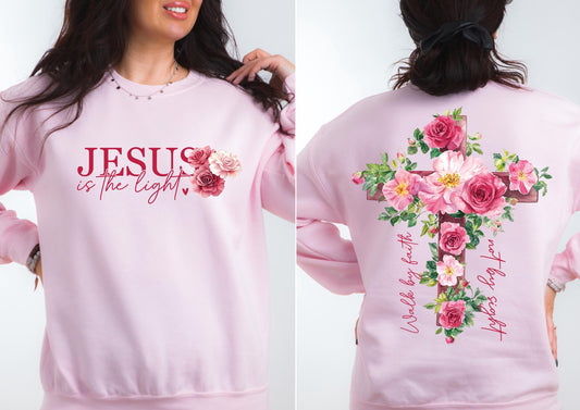 May include: A light pink sweatshirt with the text "JESUS is the light" and a floral design. The back features a cross adorned with pink roses and the text "Walk by faith, not by sight."