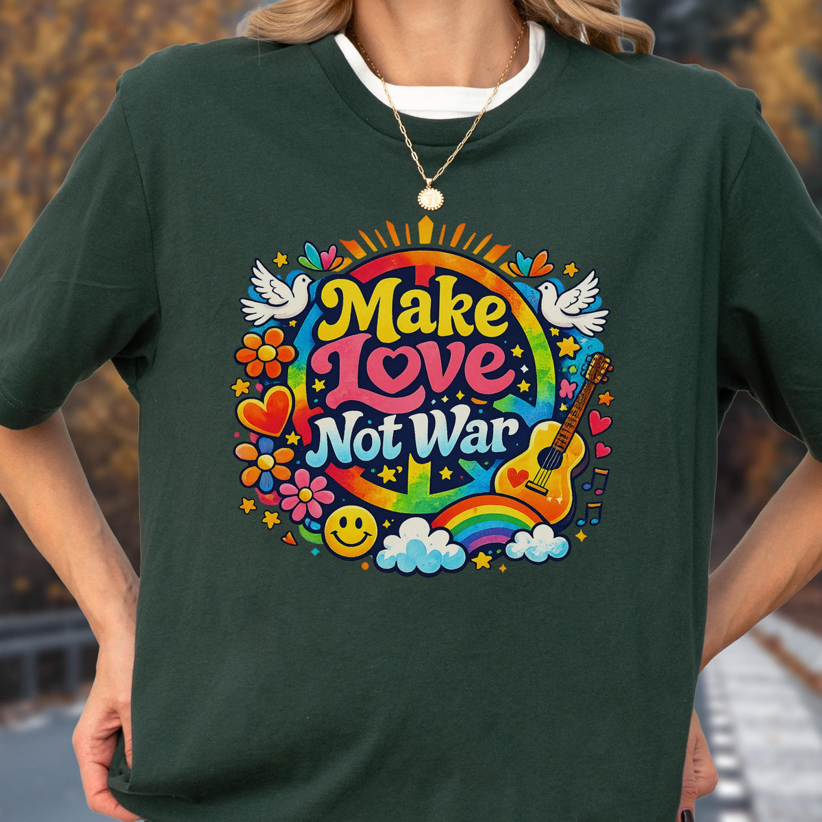 May include: Dark green t-shirt with a colorful graphic that says "Make Love Not War." The design includes a peace sign, rainbow, flowers, doves, a guitar, and a smiley face. The shirt has a round neckline.