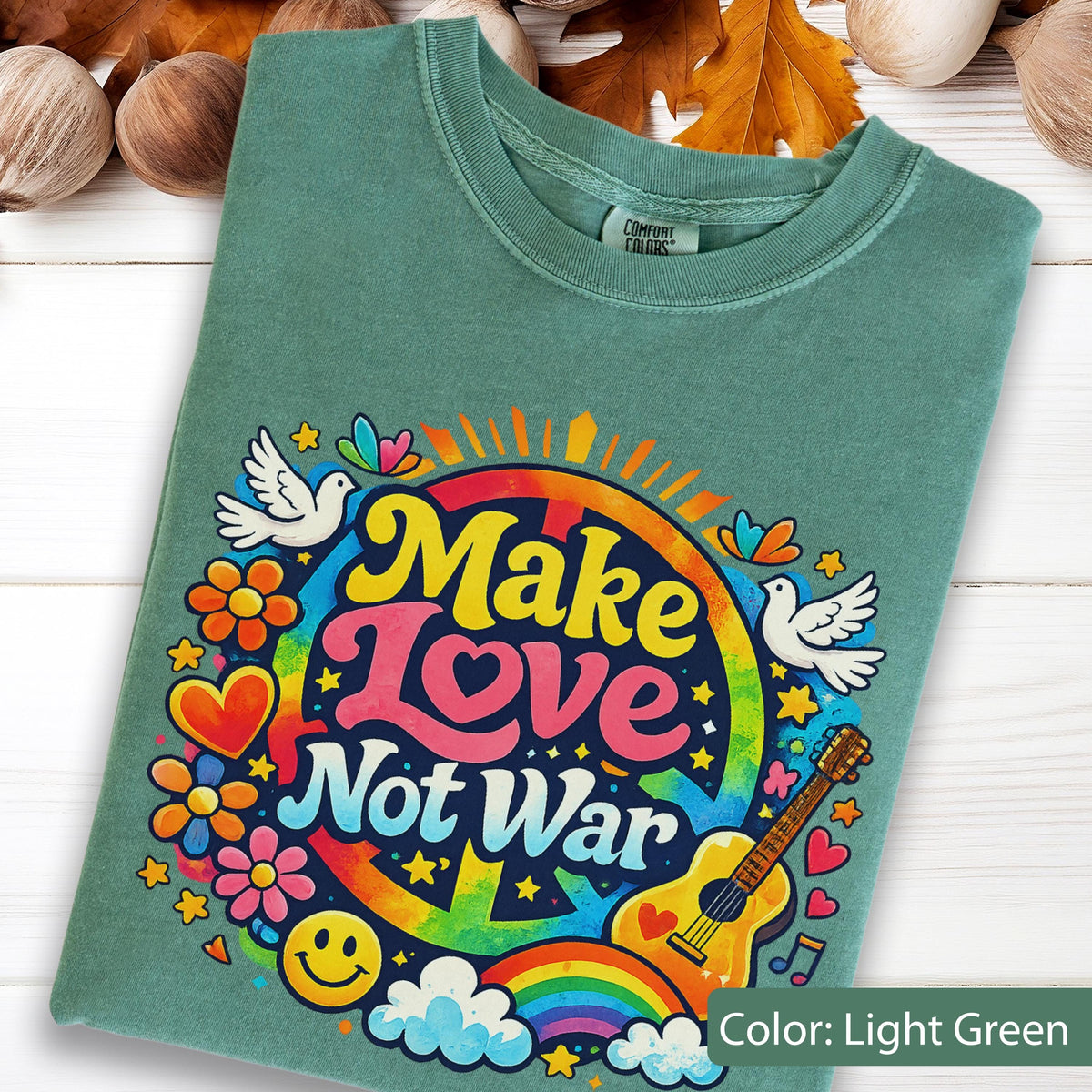 May include: Light green t-shirt with a colorful graphic that says "Make Love Not War". The design includes a peace sign, rainbow, guitar, doves, flowers, and a smiley face. The shirt is a Comfort Colors brand.