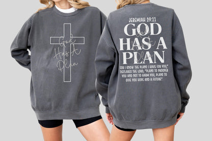May include: A charcoal gray sweatshirt with the text "God Has A Plan" and a cross design on the front. The back of the sweatshirt features the text "Jeremiah 29:11" and a longer quote about hope and the future.