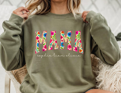 May include: Olive green sweatshirt with the word "MAMA" in large, floral-filled letters. Below the word "MAMA" are the names "sophie liam olivia" in a delicate script. The sweatshirt is a casual, comfortable style.