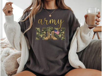 May include: Dark gray sweatshirt with the words "army mom" in gold script and camouflage block letters. The "M"s feature a military hat, boots, and an American flag. A cozy, off-white cardigan is draped over the shoulders.