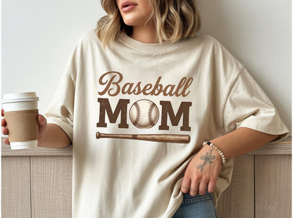 May include: Beige baseball mom t-shirt with a brown graphic. The graphic includes the words "Baseball MOM", a baseball, and a baseball bat. The shirt is a casual, oversized fit.