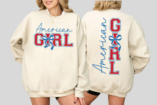 May include: Cream-colored sweatshirt with the text "American GIRL" in red and blue. The front features the text in a script font and block letters with a bow graphic. The back has the same text vertically.