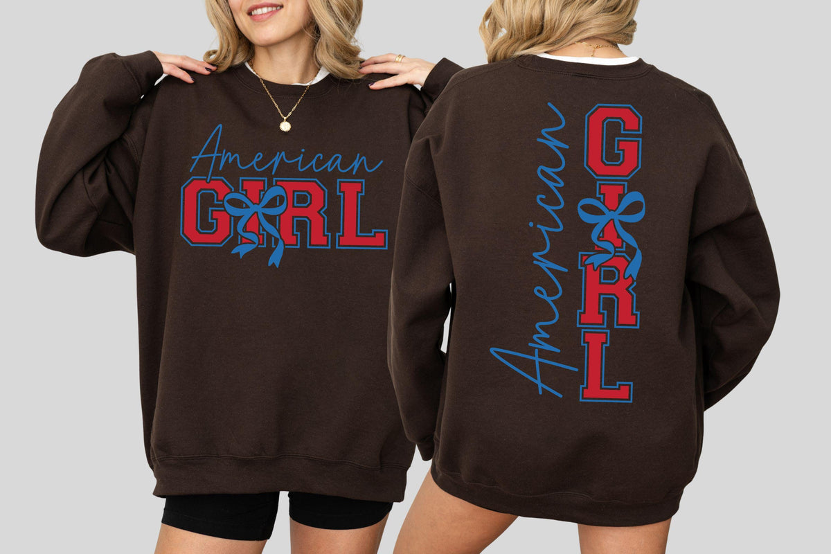 May include: A brown sweatshirt with the words "American GIRL" in red and blue lettering. The front of the sweatshirt has the words "American GIRL" in a script font and block letters. The back of the sweatshirt has the words "American GIRL" vertically.