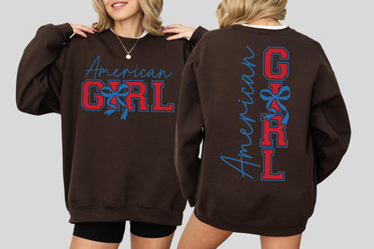 May include: A brown sweatshirt with the words "American GIRL" in red and blue lettering. The front of the sweatshirt has the words "American GIRL" in a script font and block letters. The back of the sweatshirt has the words "American GIRL" vertically.