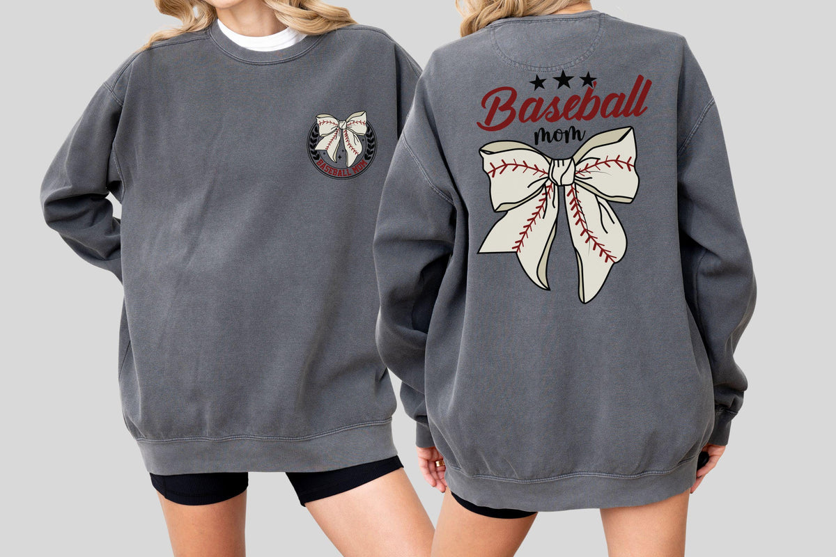 May include: A charcoal gray sweatshirt with a white crew neck peeking out. The front features a bow design within a circular emblem. The back displays the words "Baseball mom" above a large bow design with baseball stitching.