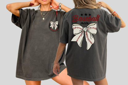 May include: Dark gray oversized t-shirt featuring a baseball-themed design. The front has a bow graphic with a baseball stitch design. The back of the shirt has the words "Baseball mom" with a bow graphic.