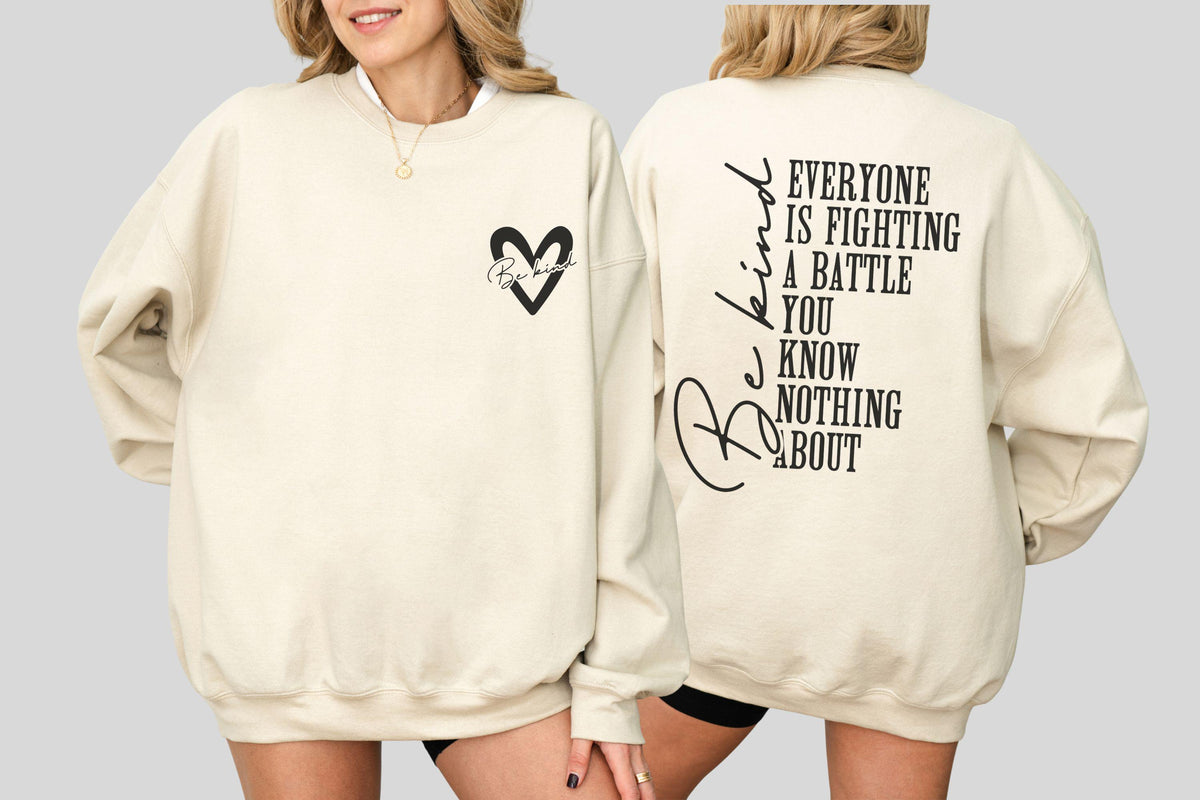 May include: Cream-colored sweatshirt with a black heart graphic and the words "Be Kind" inside. The back of the sweatshirt features the phrase "Everyone is fighting a battle you know nothing about" in black lettering.