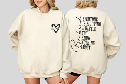 May include: Cream-colored sweatshirt with a black heart graphic and the words "Be Kind" inside. The back of the sweatshirt features the phrase "Everyone is fighting a battle you know nothing about" in black lettering.