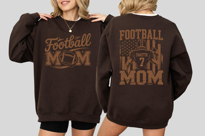 May include: A dark brown sweatshirt with the words "Football MOM" in a brown, stylized font. The front of the sweatshirt features a football graphic. The back of the sweatshirt has a football player graphic and the words "Football MOM".