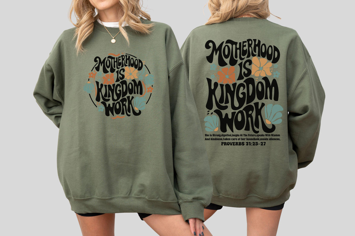 May include: Olive green sweatshirt with the text "Motherhood is Kingdom Work" in a retro font, surrounded by floral designs in orange, blue, and white. The back of the sweatshirt repeats the design and includes a Bible verse.