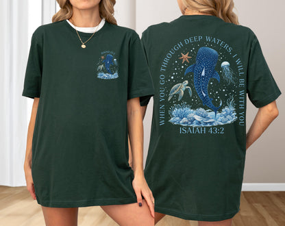 May include: Dark green t-shirt with a marine life design. The front features a whale shark and text. The back has a larger design with a whale shark, turtle, and jellyfish, with the text "WHEN YOU GO THROUGH DEEP WATERS, I WILL BE WITH YOU" and "ISAIAH 43:2".
