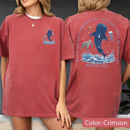 May include: Crimson-colored t-shirt featuring a front and back design. The front displays a blue whale illustration with the text "When you go through deep waters, I will be with you. Isaiah 43:2" on the back. The shirt is a short-sleeved, casual style.