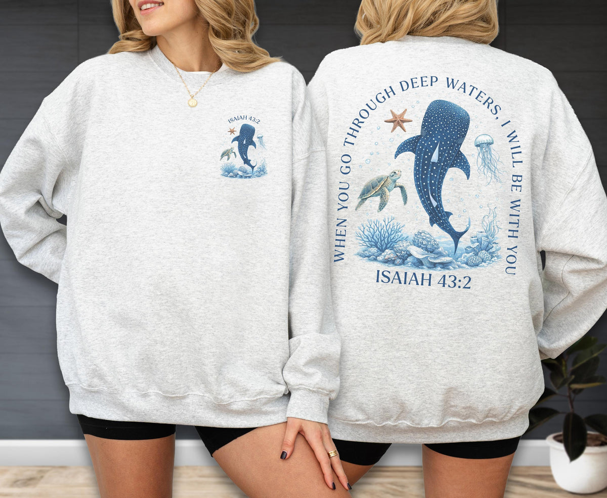 May include: Light gray sweatshirt with a blue marine life design. The front features a whale shark, and the text "Isaiah 43:2". The back has a larger design with a whale shark, turtle, jellyfish, and the text "When you go through deep waters, I will be with you. Isaiah 43:2".