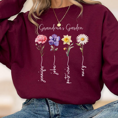 May include: Burgundy sweatshirt with the text "Grandma's Garden" and four colorful flower illustrations. Each flower has a name written below it: Jennifer, John, Patricia, and Mary. A gold necklace is visible.