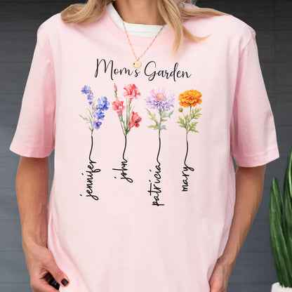 May include: Pink t-shirt with the text "Mom's Garden" and floral illustrations. The shirt features four flowers with names: Jennifer, John, Patricia, and Mary. The flowers are in shades of blue, red, purple, and orange.