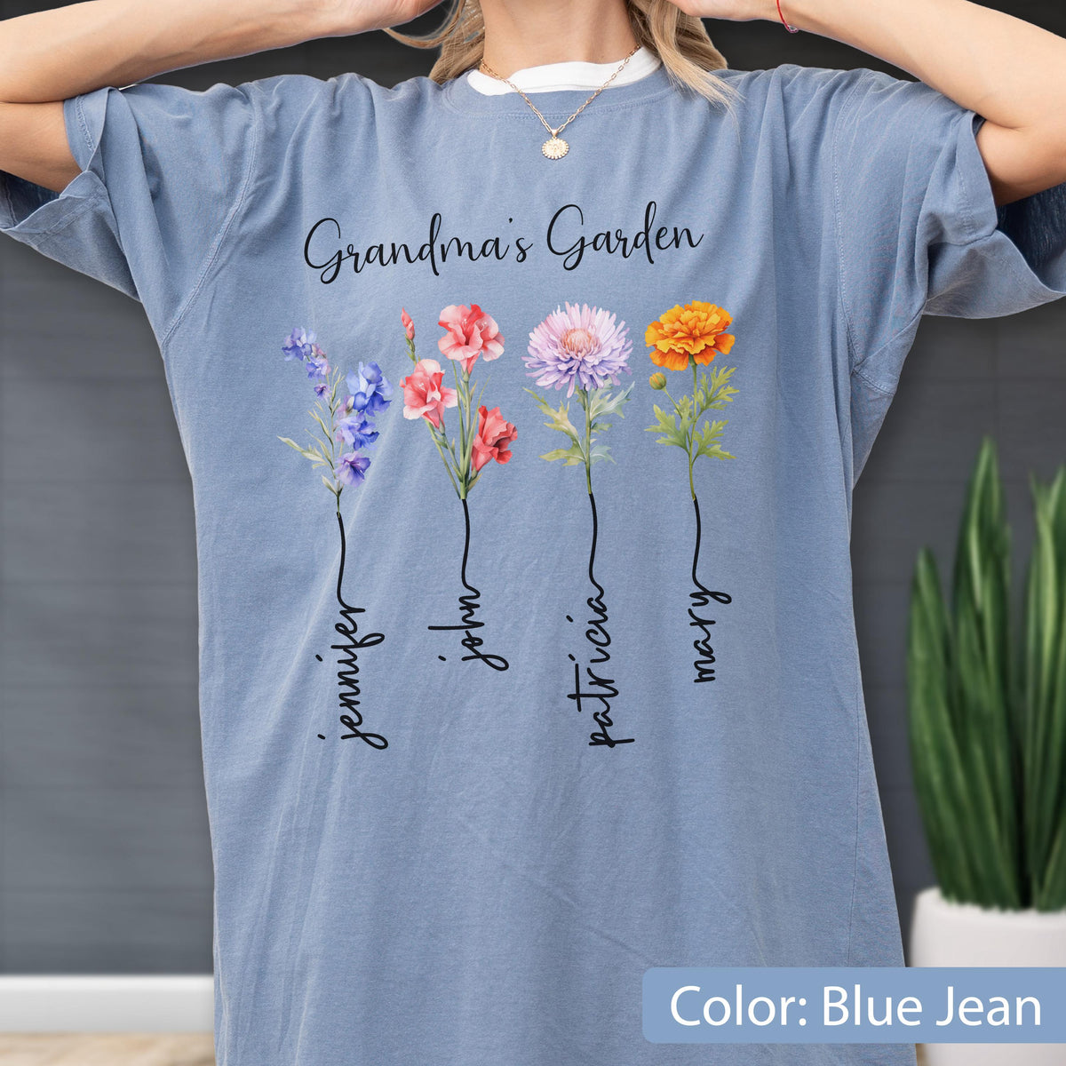 May include: Blue jean colored t-shirt with the text "Grandma's Garden" and four colorful flower illustrations. Each flower has a name written below it: Jennifer, John, Patricia, and Mary.