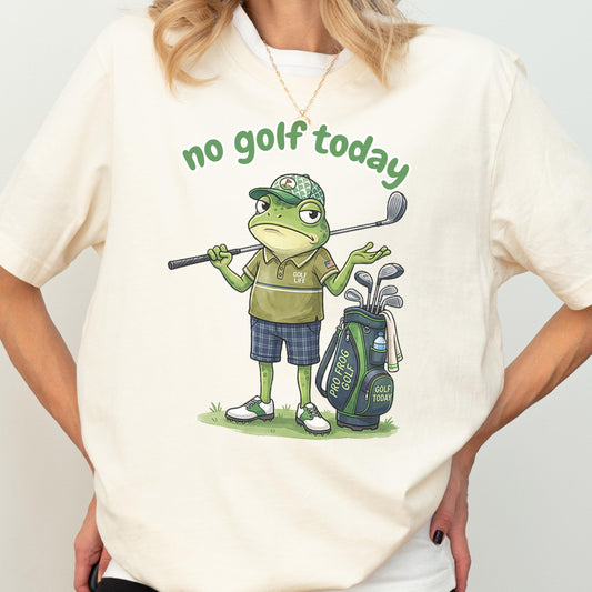 Cream unisex t-shirt with a funny cartoon frog dressed as a golfer holding a club next to a golf bag, with the text no golf today, perfect humorous gift for golf lovers and frog fans