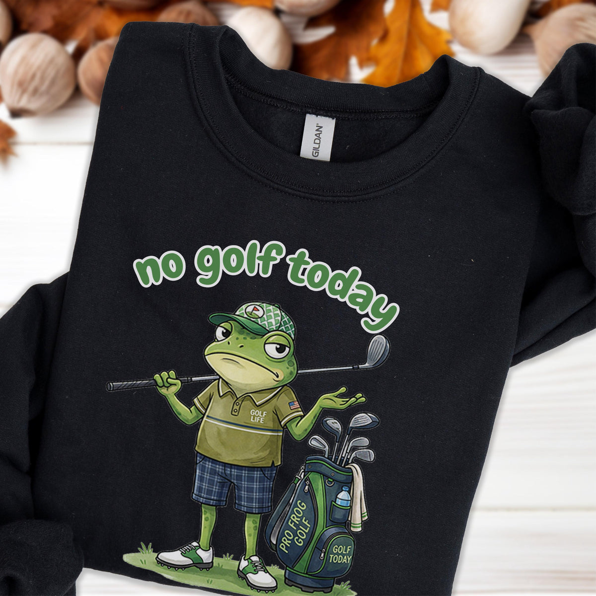 May include: Black sweatshirt with a cartoon frog golfer and the text "no golf today" in green. The frog is wearing a golf hat and holding a golf club. A golf bag with clubs is next to the frog.
