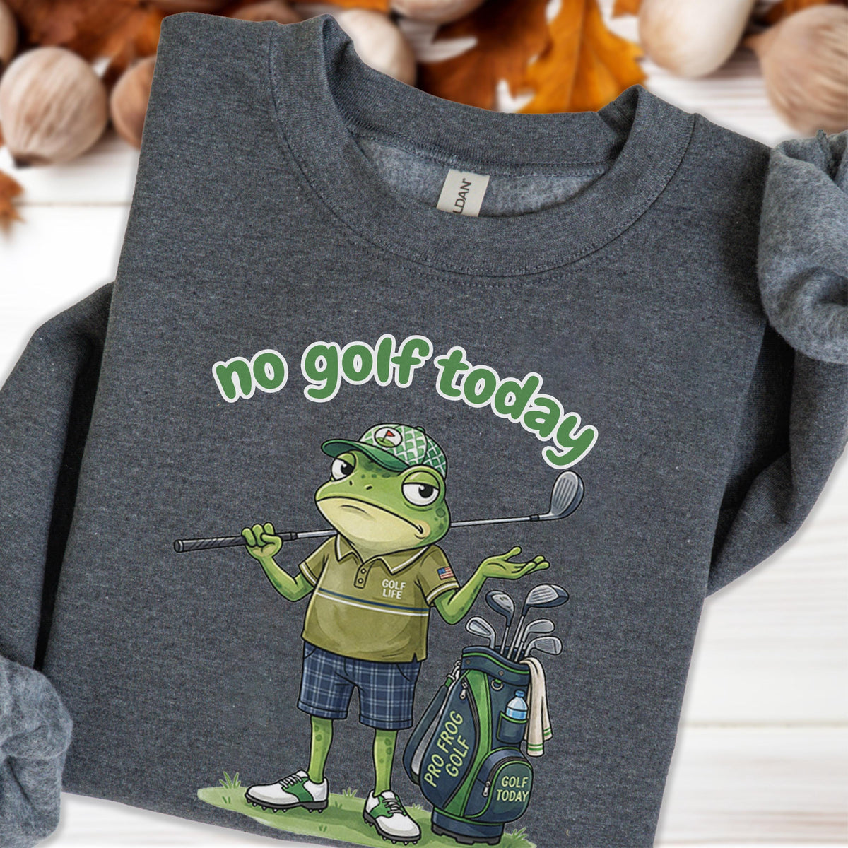 May include: Dark gray sweatshirt with a cartoon frog golfer. The frog is wearing a golf hat, polo shirt, and plaid shorts, holding a golf club. Text reads "no golf today" and "Golf Life". A golf bag is next to the frog.