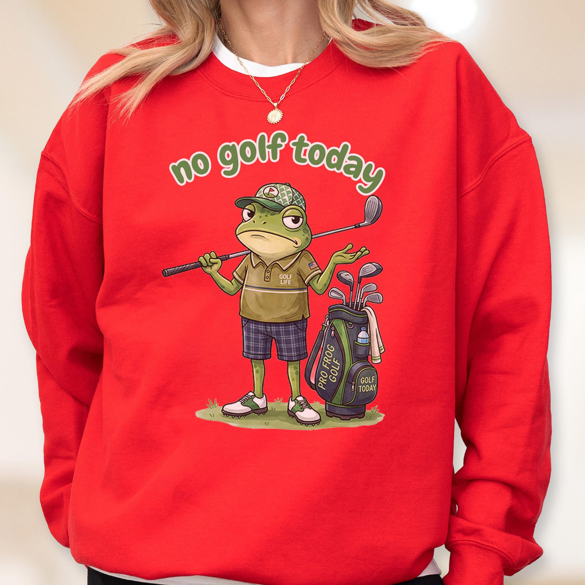 May include: Red sweatshirt with the phrase "no golf today" in green script. The graphic features a frog wearing a golf hat and holding a golf club, with a golf bag and clubs nearby. The frog is wearing a golf shirt and plaid shorts.