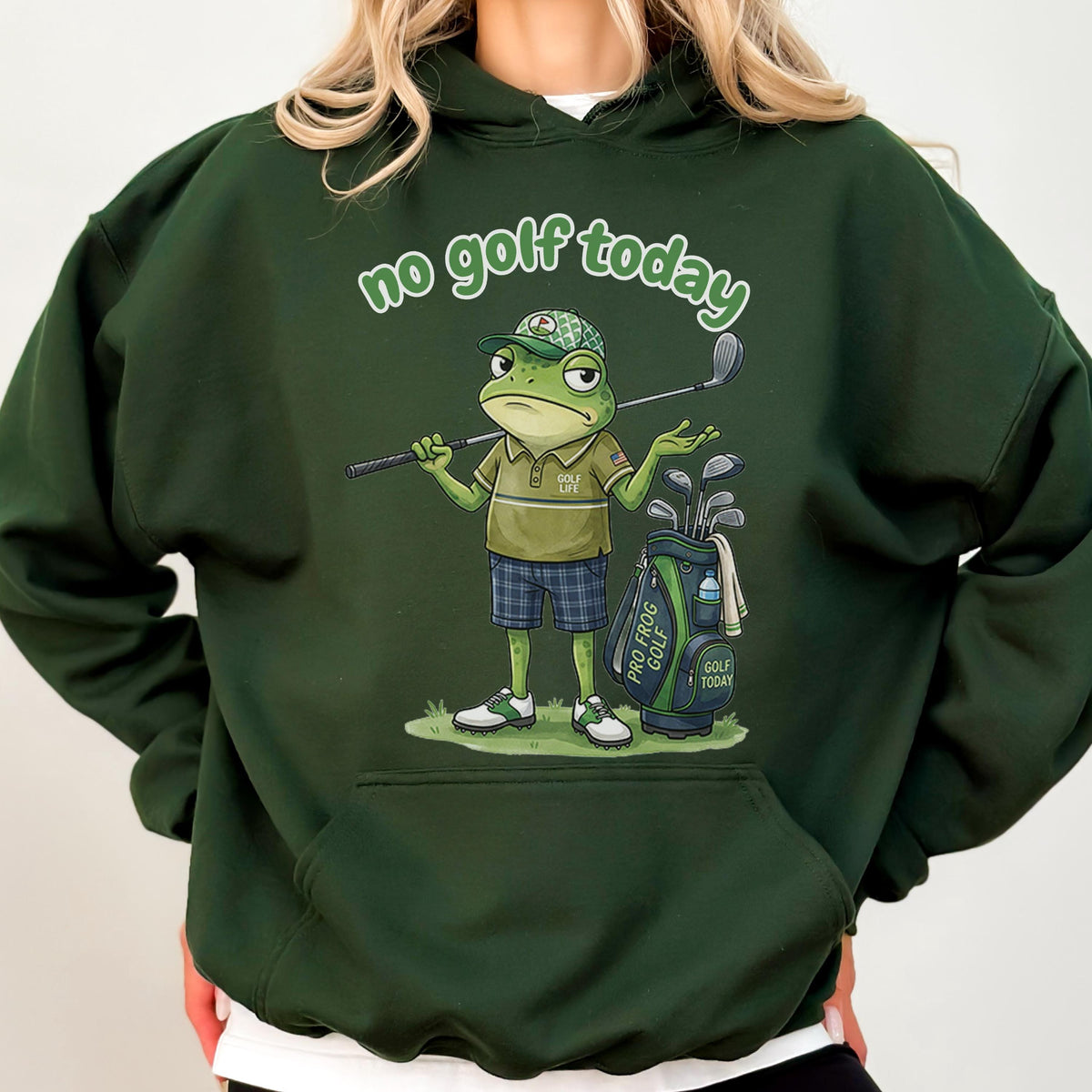 May include: Dark green hoodie featuring a cartoon frog with golf clubs and a golf bag. The frog is wearing a golf hat, polo shirt, and plaid shorts. The text "no golf today" is arched above the frog.