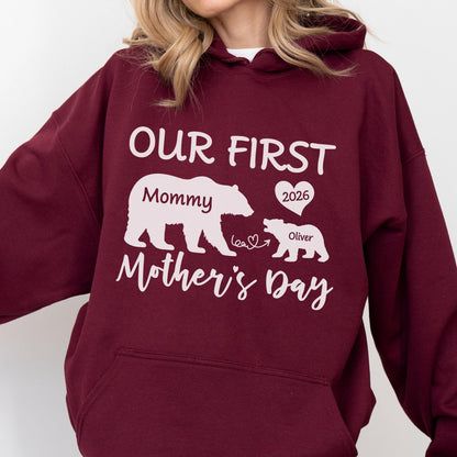 May include: A maroon hoodie with white text and graphics. The text reads "OUR FIRST Mother's Day" with a bear graphic labeled "Mommy" and a smaller bear labeled "Oliver" with a heart and the year "2026".