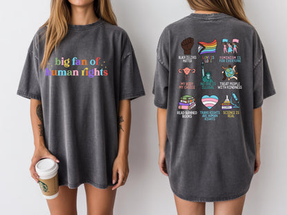 May include: Dark gray t-shirt with the text "big fan of human rights" in rainbow colors on the front. The back features various graphic icons and phrases, including "Black Lives Matter" and "Trans Rights are Human Rights."