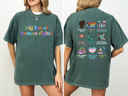 May include: A dark green t-shirt with the text "big fan of human rights" in colorful letters on the front. The back of the shirt features various graphics and phrases, including "Black Lives Matter" and "Trans Rights Are Human Rights".