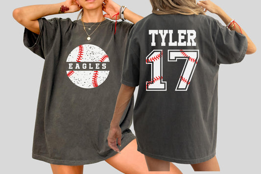 May include: Dark gray t-shirt featuring a baseball graphic with the word "EAGLES" and a baseball design. The back of the shirt displays the name "TYLER" and the number "17" with baseball stitching details. A casual, oversized fit.