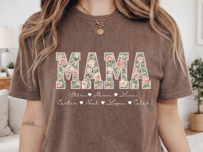 May include: Brown t-shirt with the word "MAMA" in large floral letters. Below the word "MAMA" are names with hearts. The shirt is a neutral color and has a vintage look.