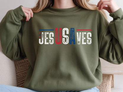 May include: An olive green sweatshirt with the text "JESUS SAVES" in white, with the "U" in red and the "S" in blue. The design has a patriotic theme.