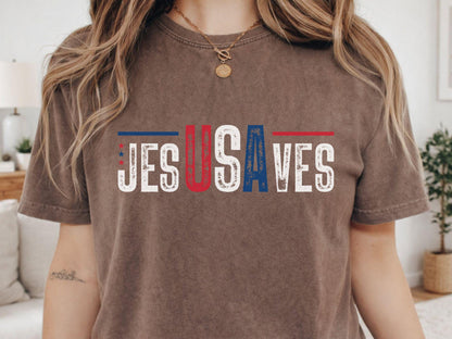 May include: A brown t-shirt with the text "JESUS SAVES" in a distressed, patriotic font. The letters are in red, white, and blue, with stars and stripes accents. The shirt has short sleeves and a crew neck.