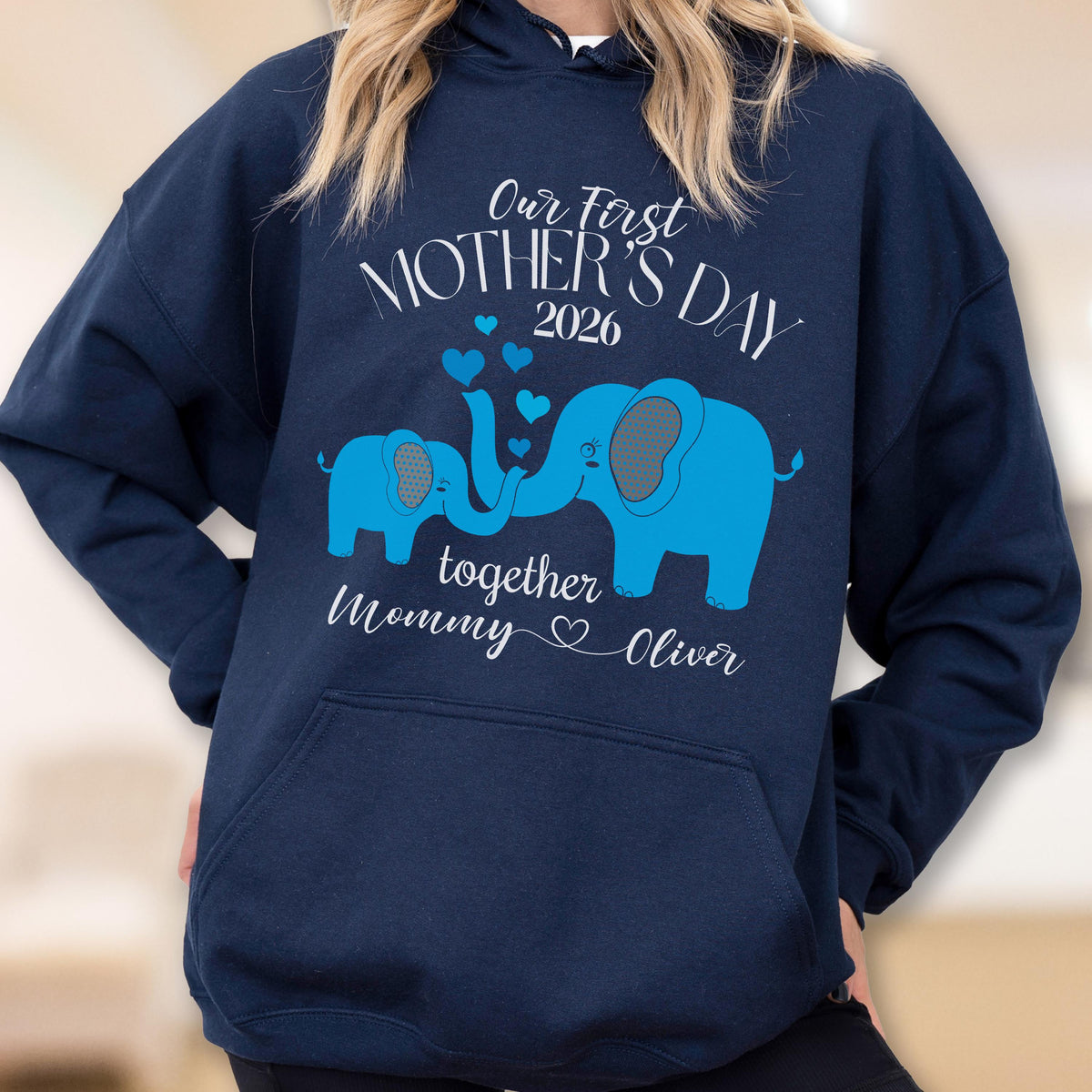 May include: Navy blue hoodie with a light blue elephant design. The design includes the text "Our First Mother's Day 2026" and "together Mommy ♡ Oliver". The hoodie has a front pocket and a drawstring hood.