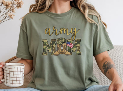 May include: Olive green t-shirt with the words "army MOM" in gold script and camouflage block letters. The design includes a military hat, boots, and an American flag. The shirt is a casual style.